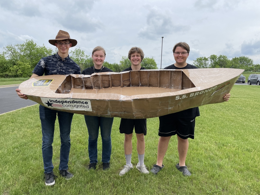 Students holding cardboard boat